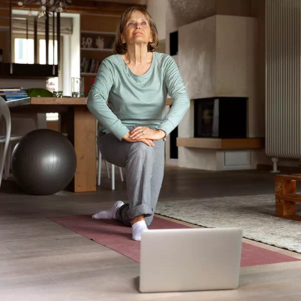 Senior suivant un cours de sport en ligne depuis son salon.