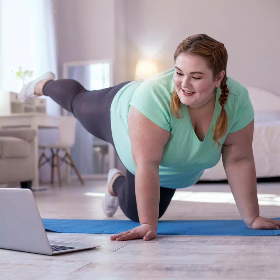 Personne en situation d'obésité réalisant des exercices physiques adaptés avec un coach en ligne.